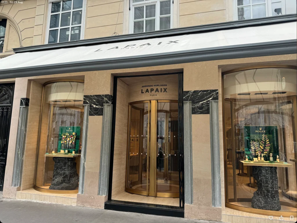Storefront displays watches, including Rolex, in large glass windows; entrance features signage "ANSHIND HORLOGER LAPAIX PARIS."