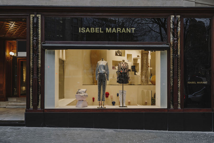 Storefront displays mannequins wearing fashionable clothing inside an Isabel Marant boutique.