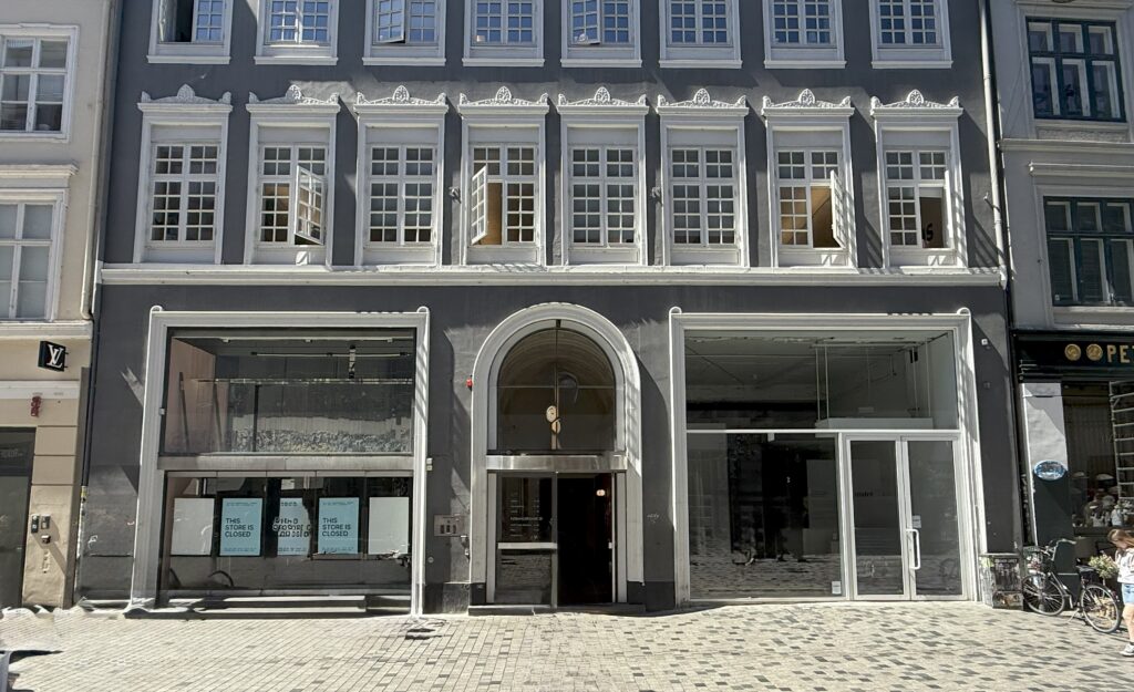 Building situated on a cobblestone street between two other structures.